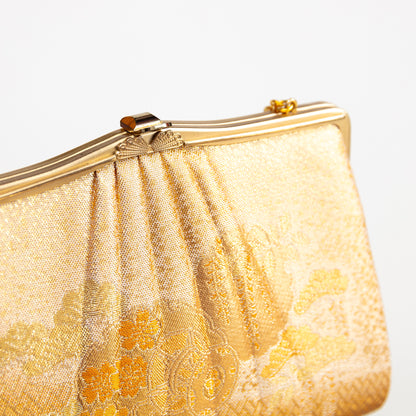 Gold clutch bag with floral patterns on a white background. Vintage Japanese evening bag circa 1970s