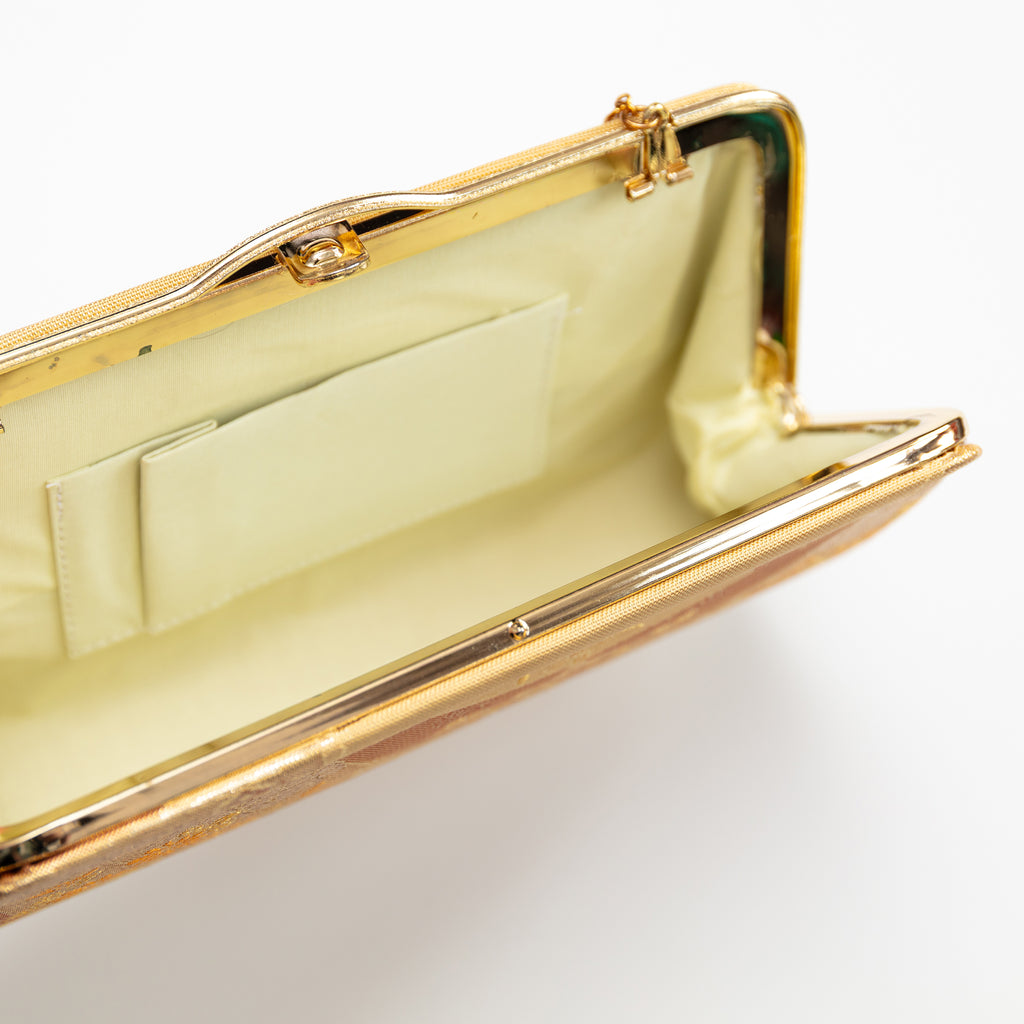 Close-up of the vintage gold silk clutch's intricate floral embroidery and subtle sheen on its textured surface.