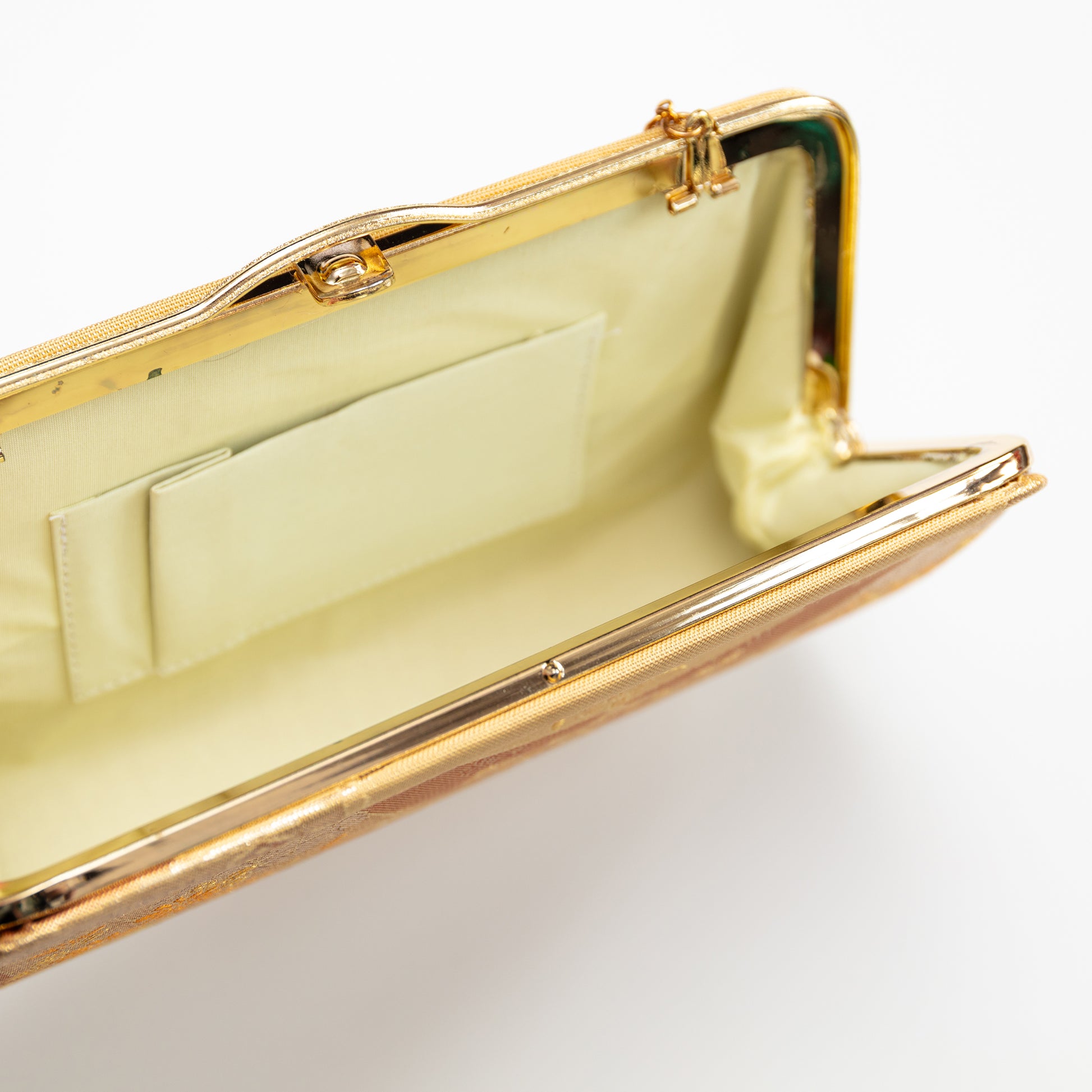 Gold clutch bag with a white interior on a light gray background