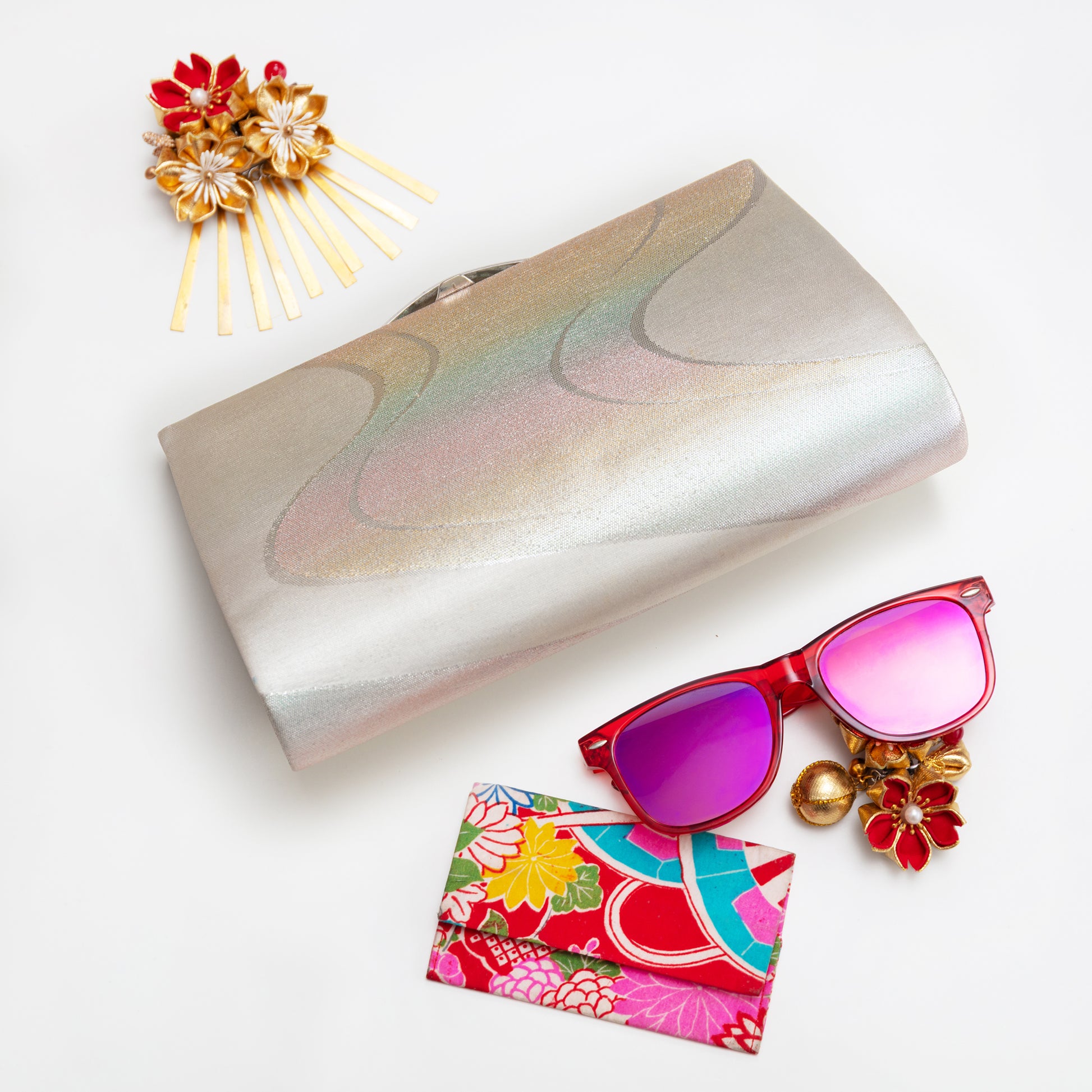 Vintage Japanese silver clutch bag with sunglasses and decorative items on a white background