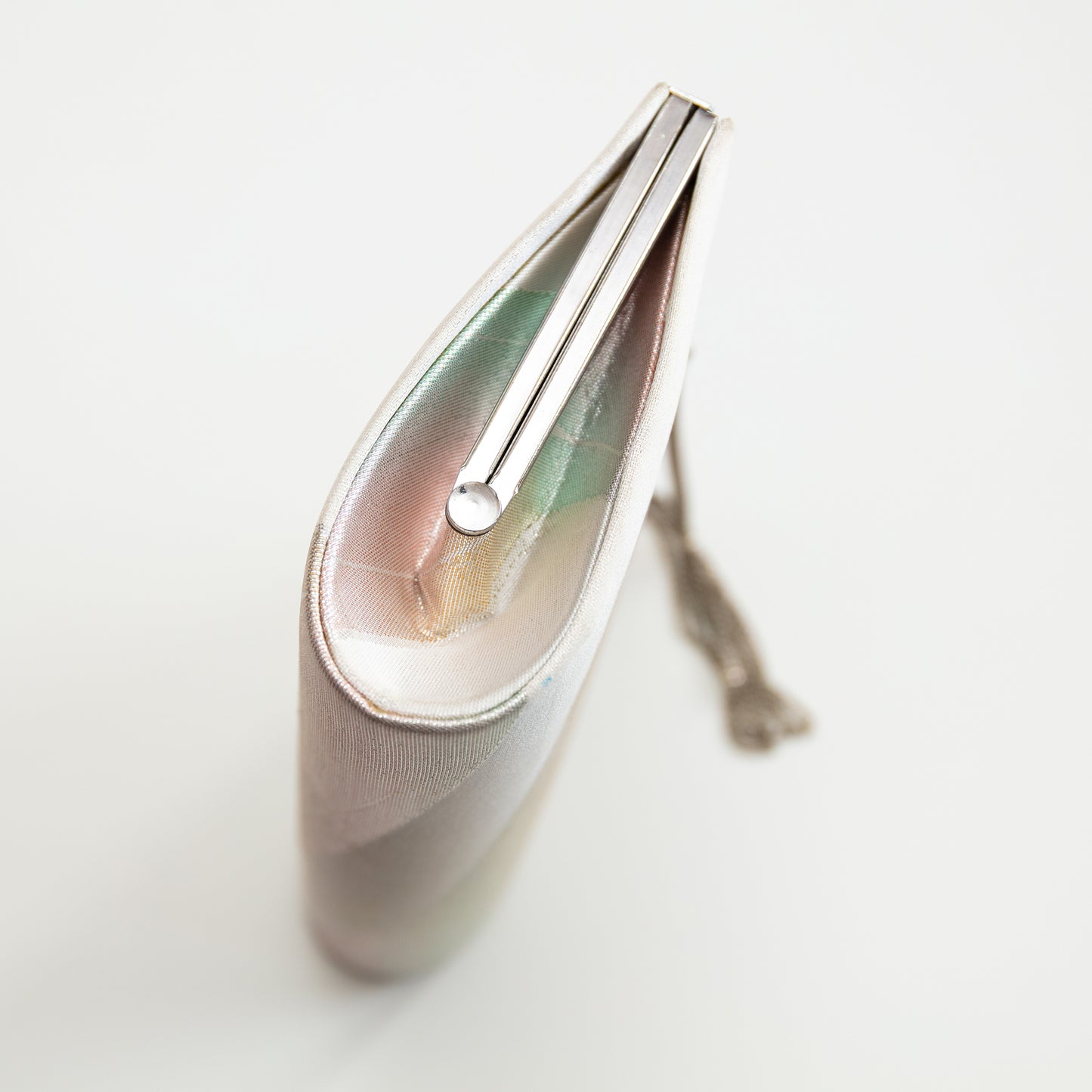Side view of metallic vintage Japanese silk clutch with silver metal frame and chain strap on white backgorund