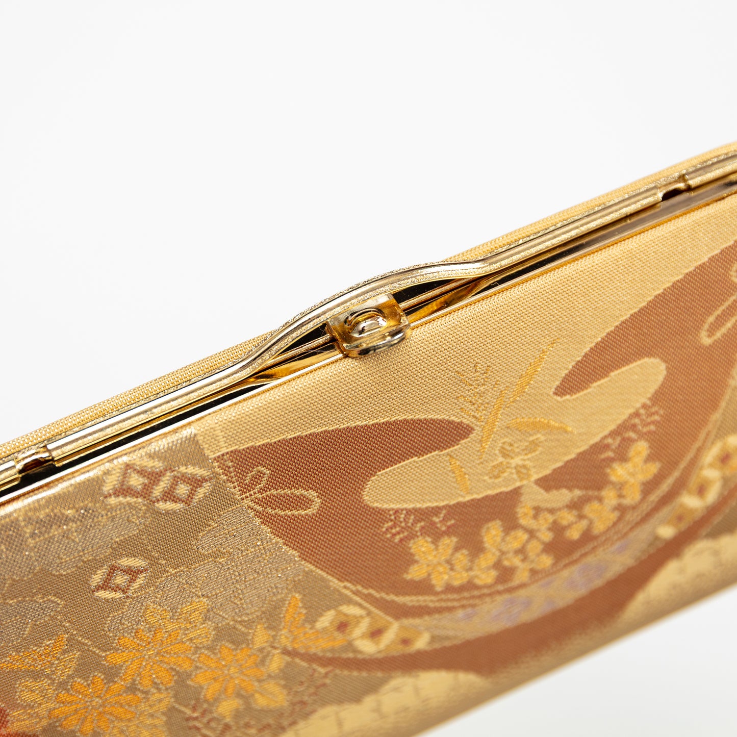 Gold clutch with floral abstract design on a white background