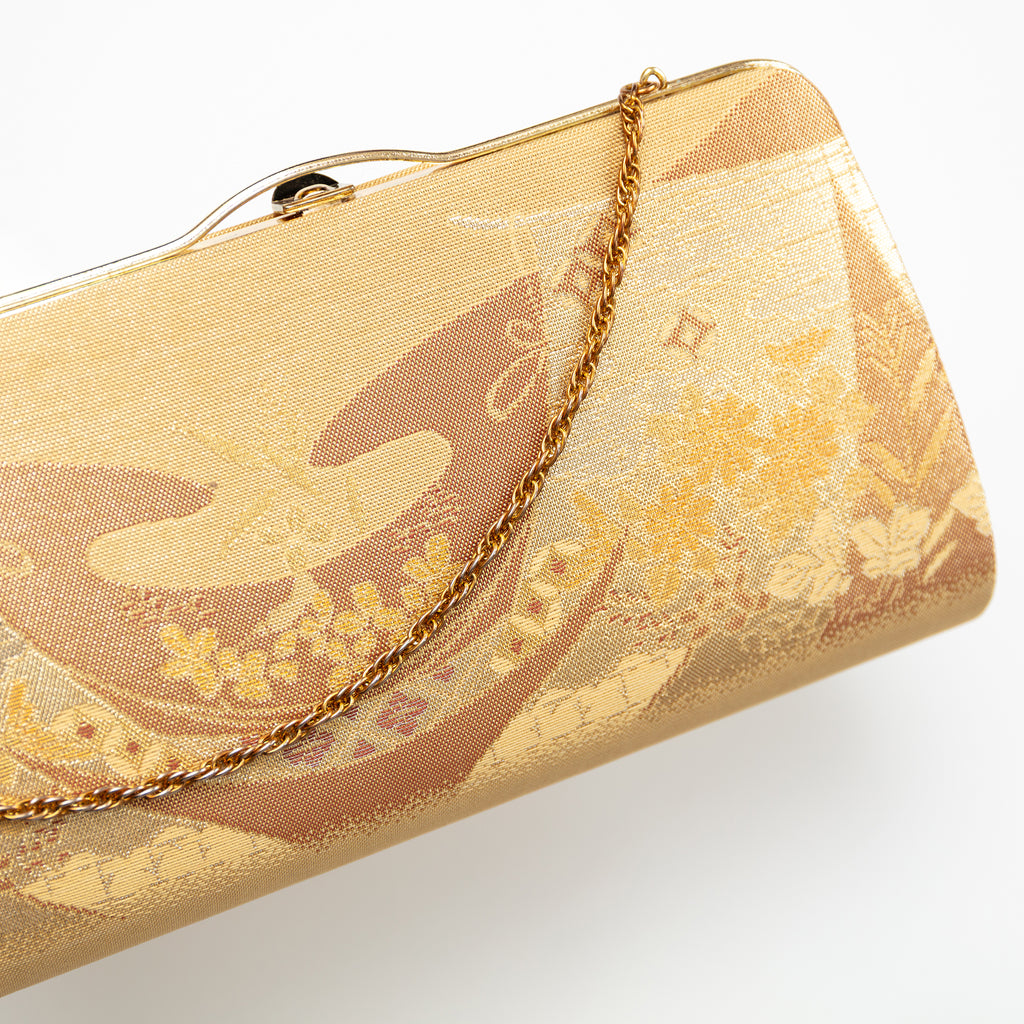 Close-up of intricate gold floral embroidery on the vintage Japanese silk clutch’s front panel, highlighting detailed