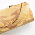 Close-up of intricate gold floral embroidery on the vintage Japanese silk clutch’s front panel, highlighting detailed