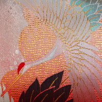 Detail of a japanese kimono pillow showing flying crane woven in pale blue metallic thread over a red silk base.