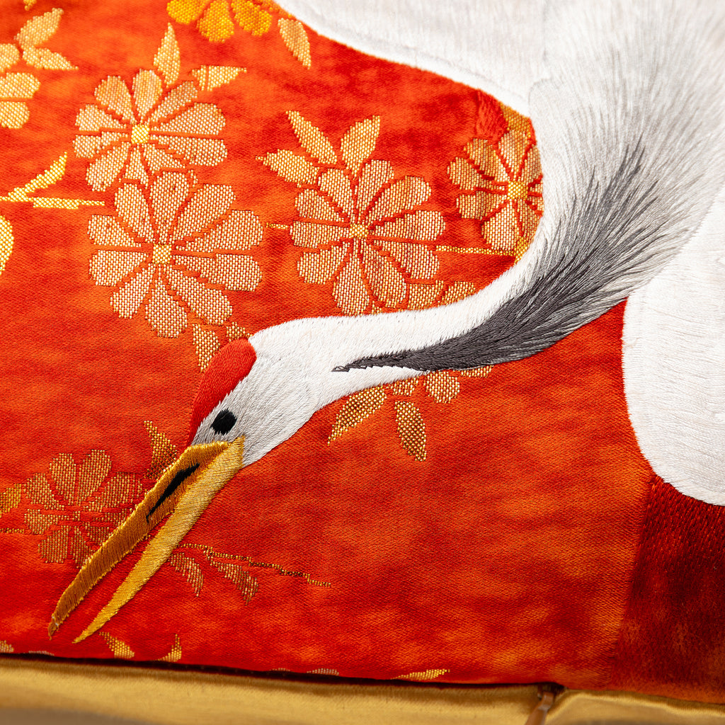Close-up of the rich gold silk fabric highlighting intricate crane embroidery and textured surface detail on the vintage red
