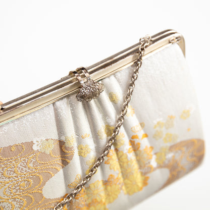 White clutch bag with gold floral pattern and chain strap on a white background