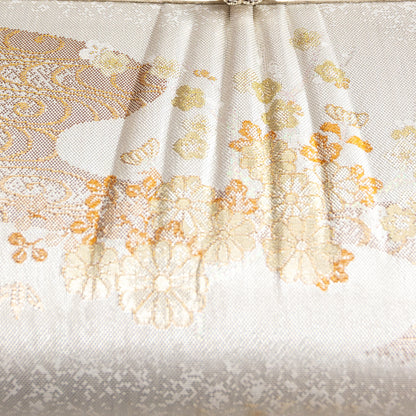Close-up of a woven kimono silk fabric with floral patterns on a white background. Detail of the clutch bag front.