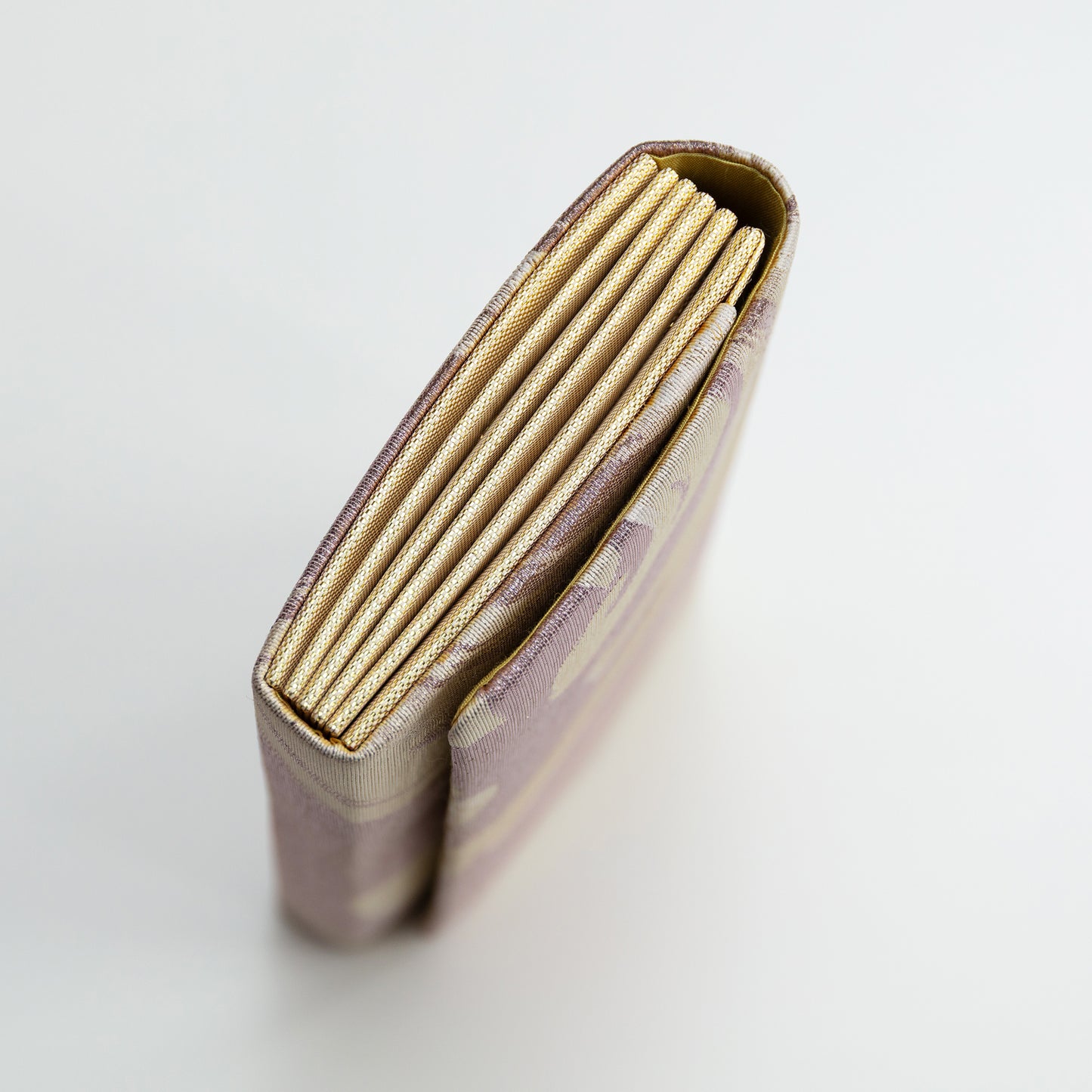 Side view of the clutch bag showing the gold brocade silk side panel on a white background.