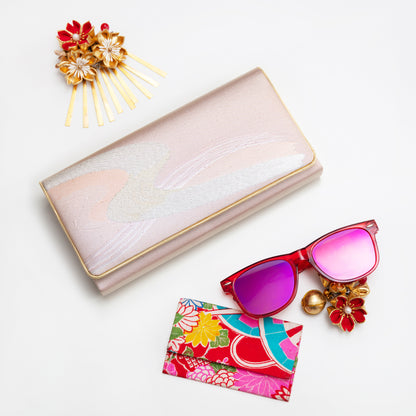 Pink vintage kimono silk wallet, with gold trim, sunglasses with pink lenses, floral cardholder, and decorative hairpin on a white background