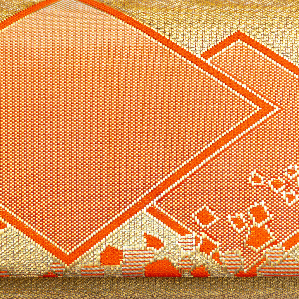 Close-up of orange diamond pattern and metallic gold fabric highlighting rich texture and intricate weave on the kimono silk