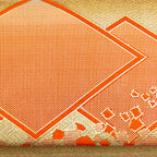 Close-up of orange diamond pattern and metallic gold fabric highlighting rich texture and intricate weave on the kimono silk