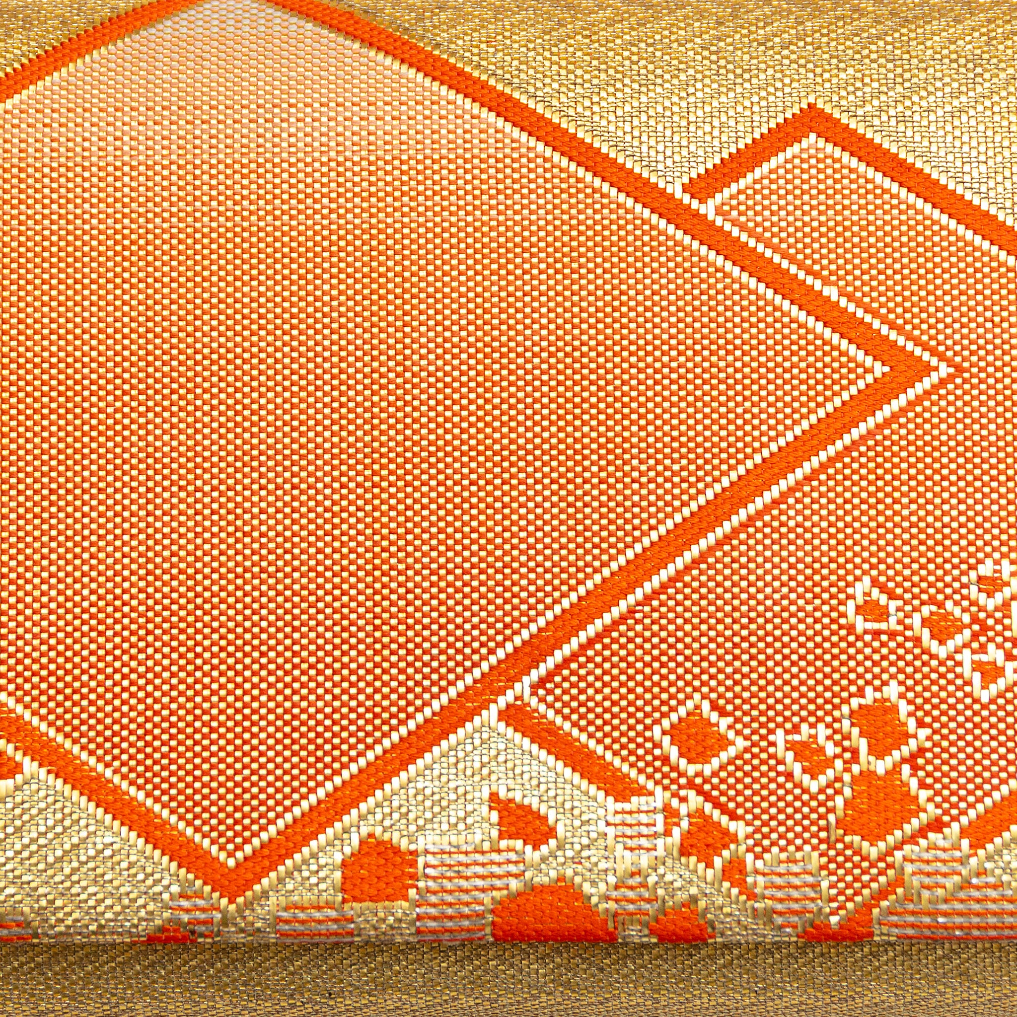 Close-up of orange diamond pattern and metallic gold fabric highlighting rich texture and intricate weave on the kimono silk
