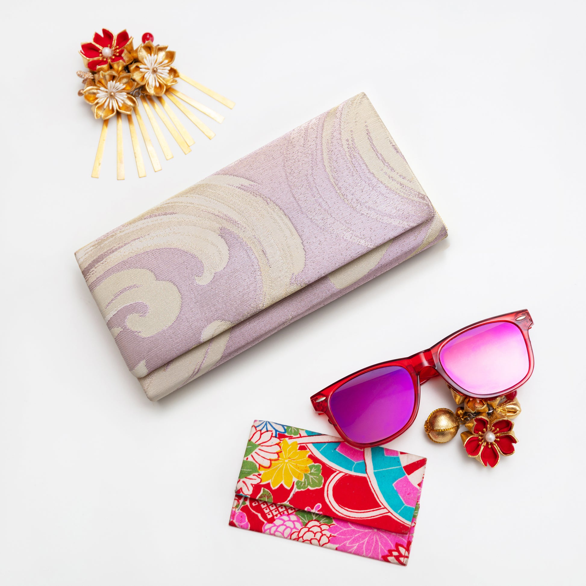 Metallic lilac pink envelope clutch bag on white background with accessories