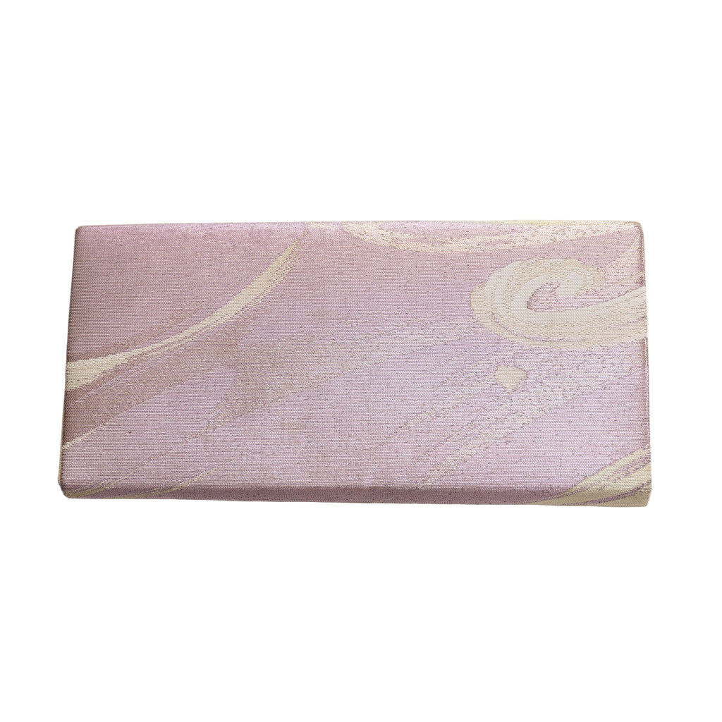 Close-up of lilac silk clutch’s delicate wave embroidery and subtle sheen, highlighting intricate craftsmanship and textured