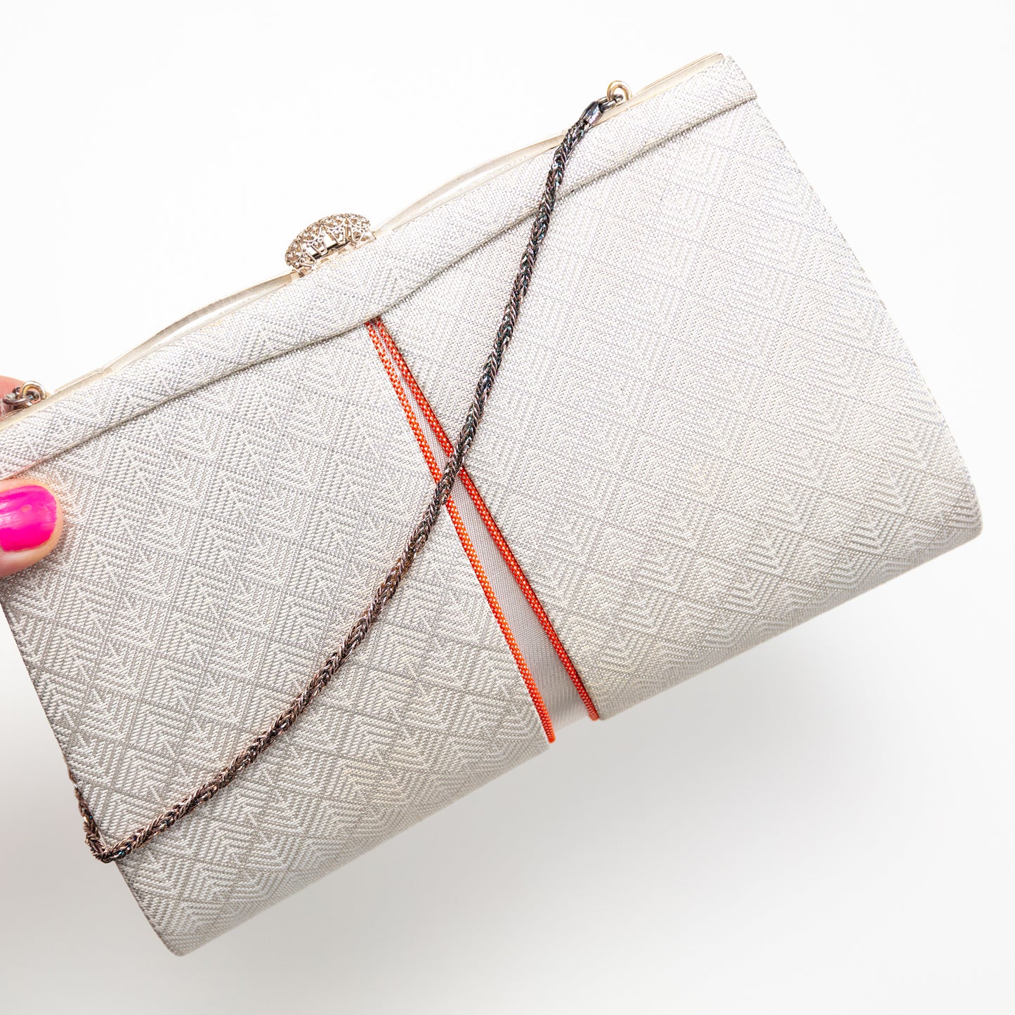 White textured vintage Japanese kimono silk clutch bag with orange accents held by a hand on a white background