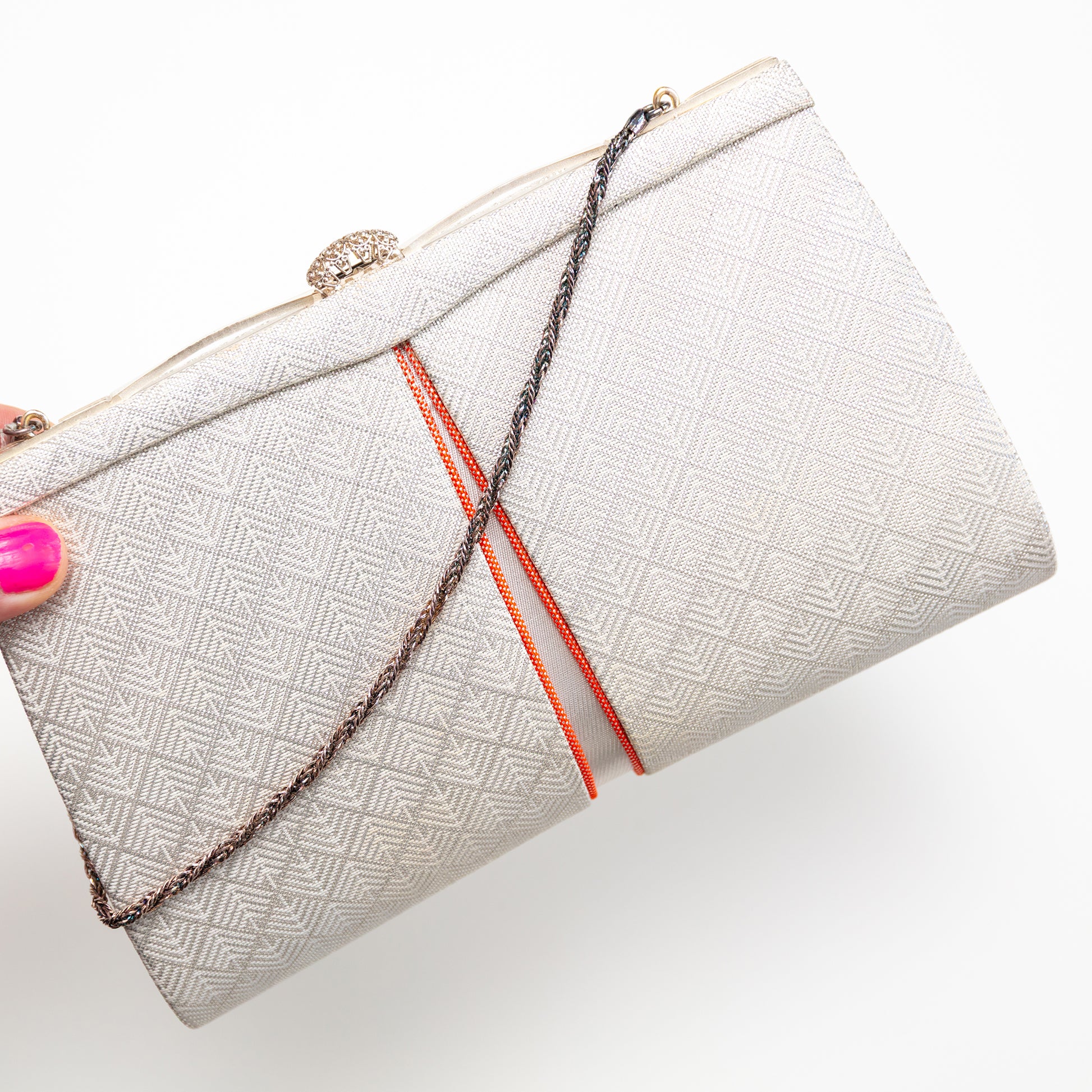 White textured vintage Japanese kimono silk clutch bag with orange accents held by a hand on a white background
