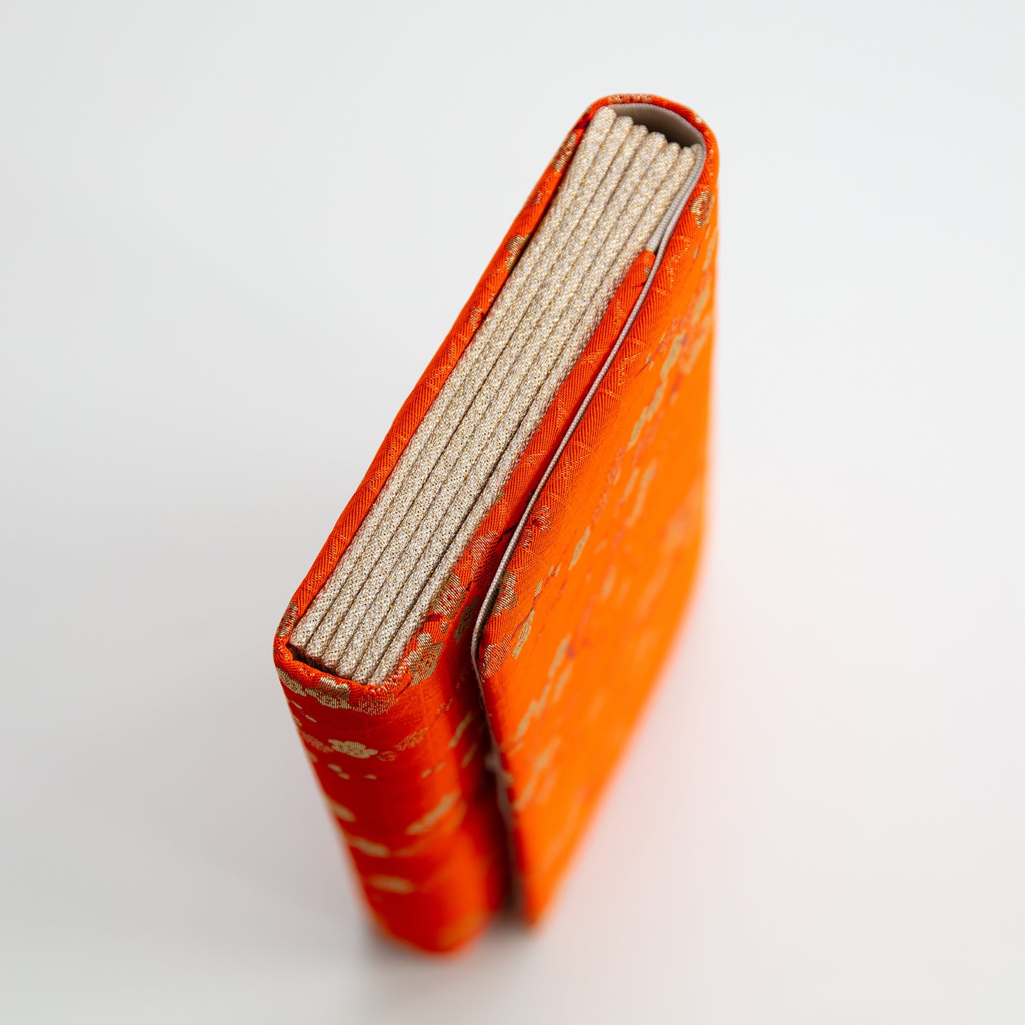 Side view of the orange and gold silk vintage Japanese clutch evening bag with gold side panels on white background.