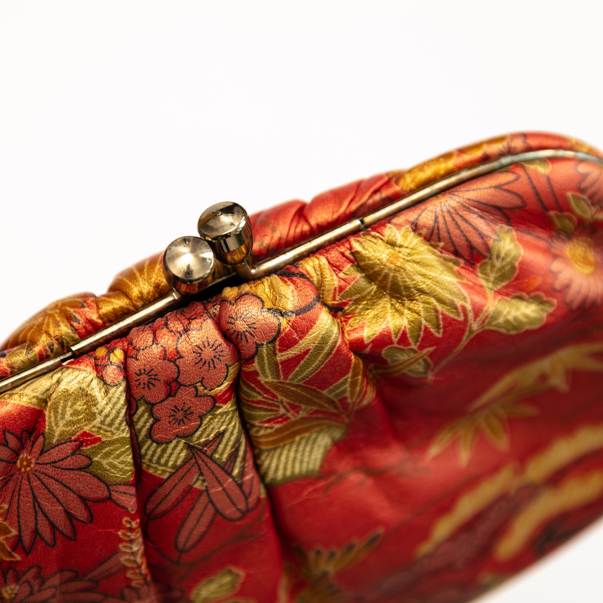 Close-up of a red and gold floral patterned clutch bag.
