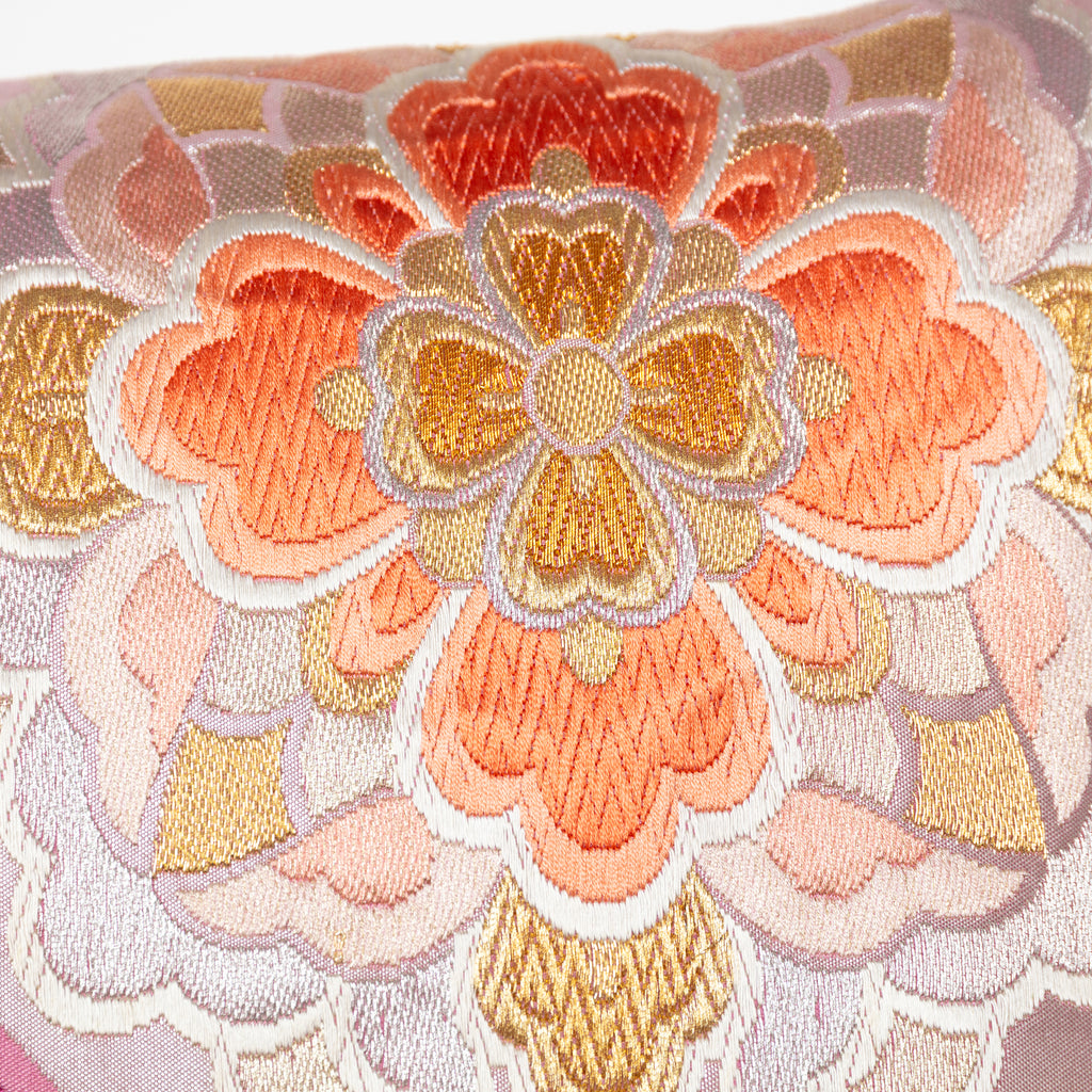 Close-up of mauve orange floral embroidered accents on silky metallic pink Obi cushion fabric detail