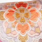 Close-up of mauve orange floral embroidered accents on silky metallic pink Obi cushion fabric detail