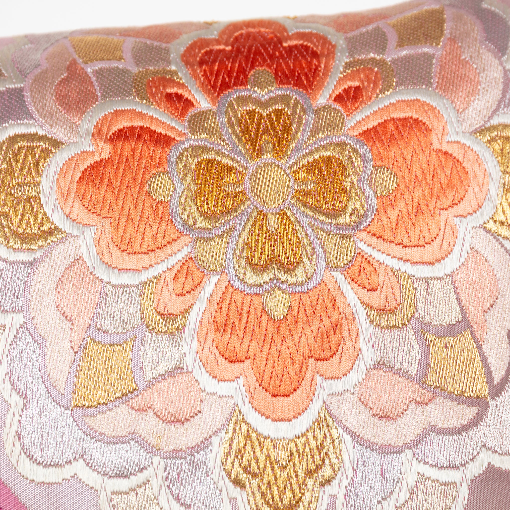 Close-up of mauve orange floral embroidered accents on silky metallic pink Obi cushion fabric detail