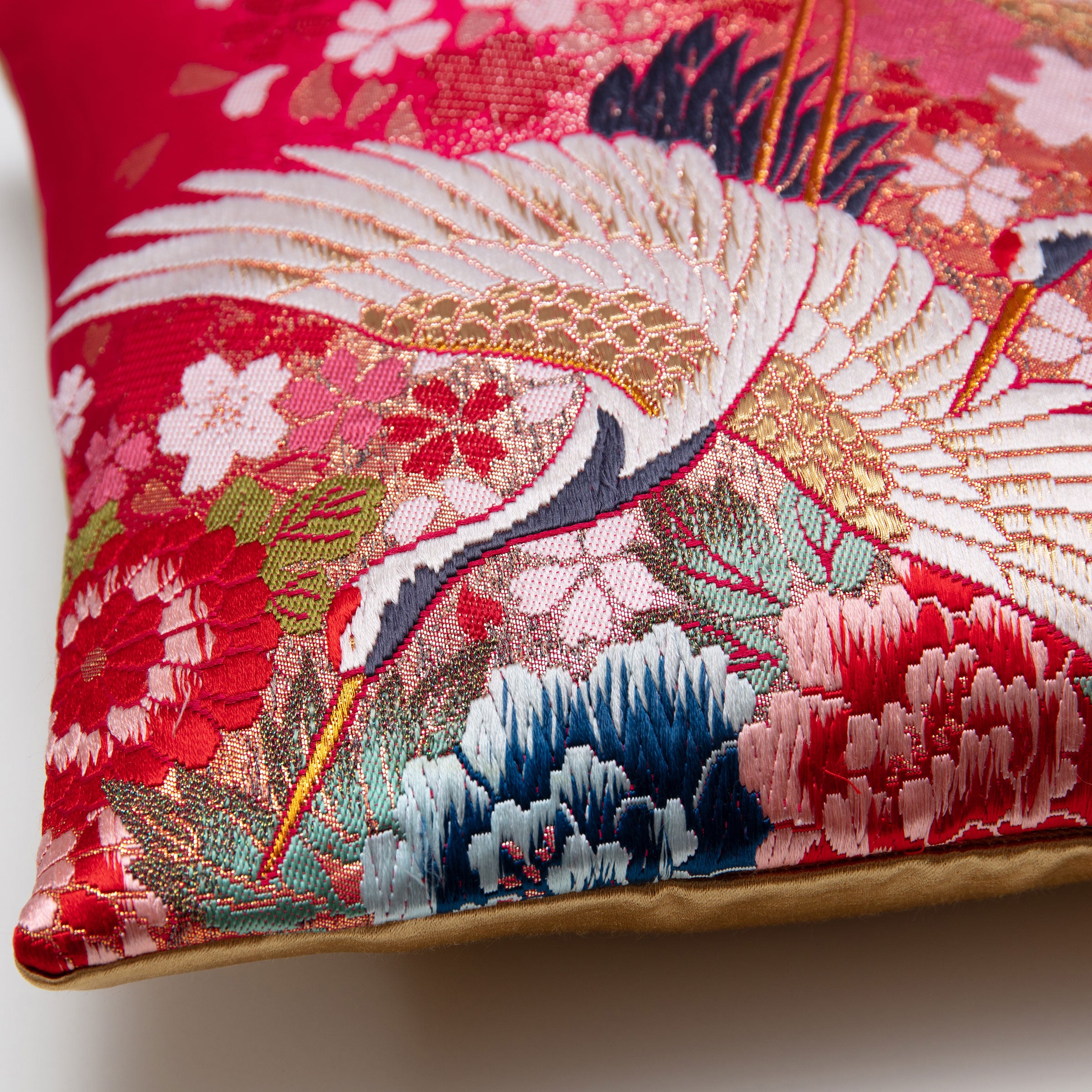 Angled detail of the pair of cranes uchikake silk cushion cover showing metallic weave and edge finish.