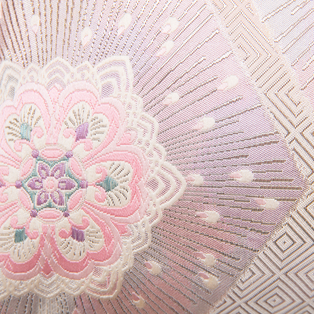 Close-up of the pink ombre silk fabric highlighting silver floral hexagon embroidery and textured diagonal stripe details
