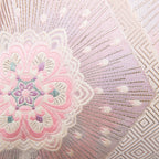 Close-up of the pink ombre silk fabric highlighting silver floral hexagon embroidery and textured diagonal stripe details