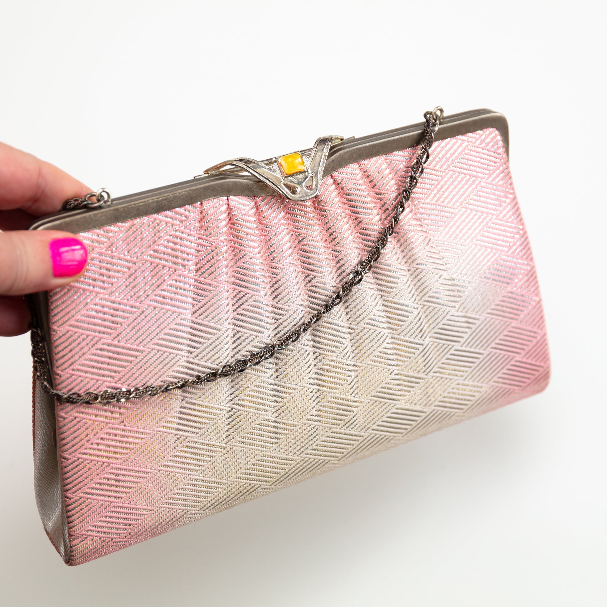 Pink and white clutch bag with a chain strap held by a hand on a white background