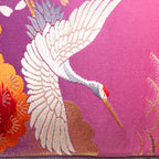 Close-up of the pink ombre floral cranes embroidery and purple velvet piping along the bolster cushion edge