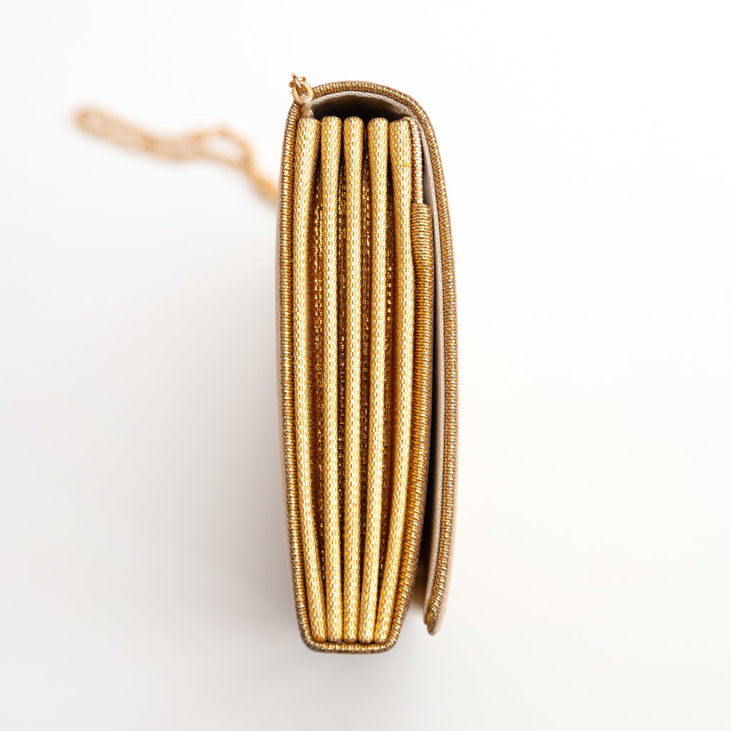 Close-up of gold foldover clutch’s floral metallic embroidery detail, highlighting textured surface and intricate stitching.