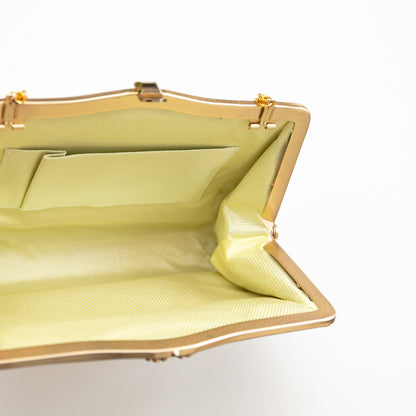 Yellow silk lined handbag with gold trim on a white background