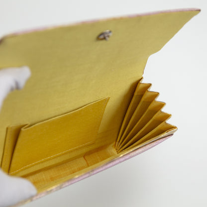 View inside the vintage clutch bag showing silk lining, internal pocket, metal fastener and some marks inside on white background.