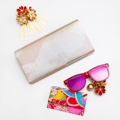 Metallic silver vintage clutch with pale pink accents on a white background with colourful accessories.