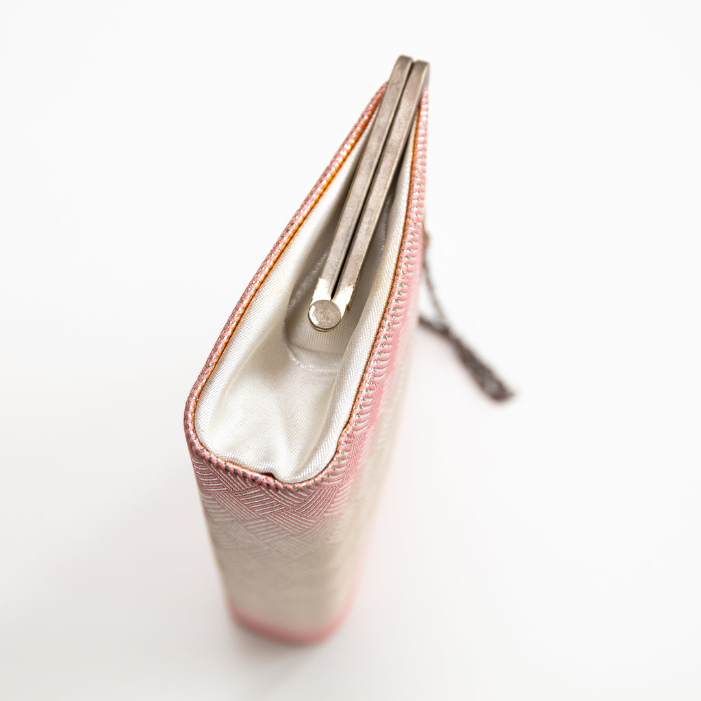 Close-up of pink silk fabric highlighting subtle ombre gradation and delicate hand-stitched embroidery details.