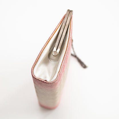 Close-up of a pink silk clutch bag with a white interior on a light gray background