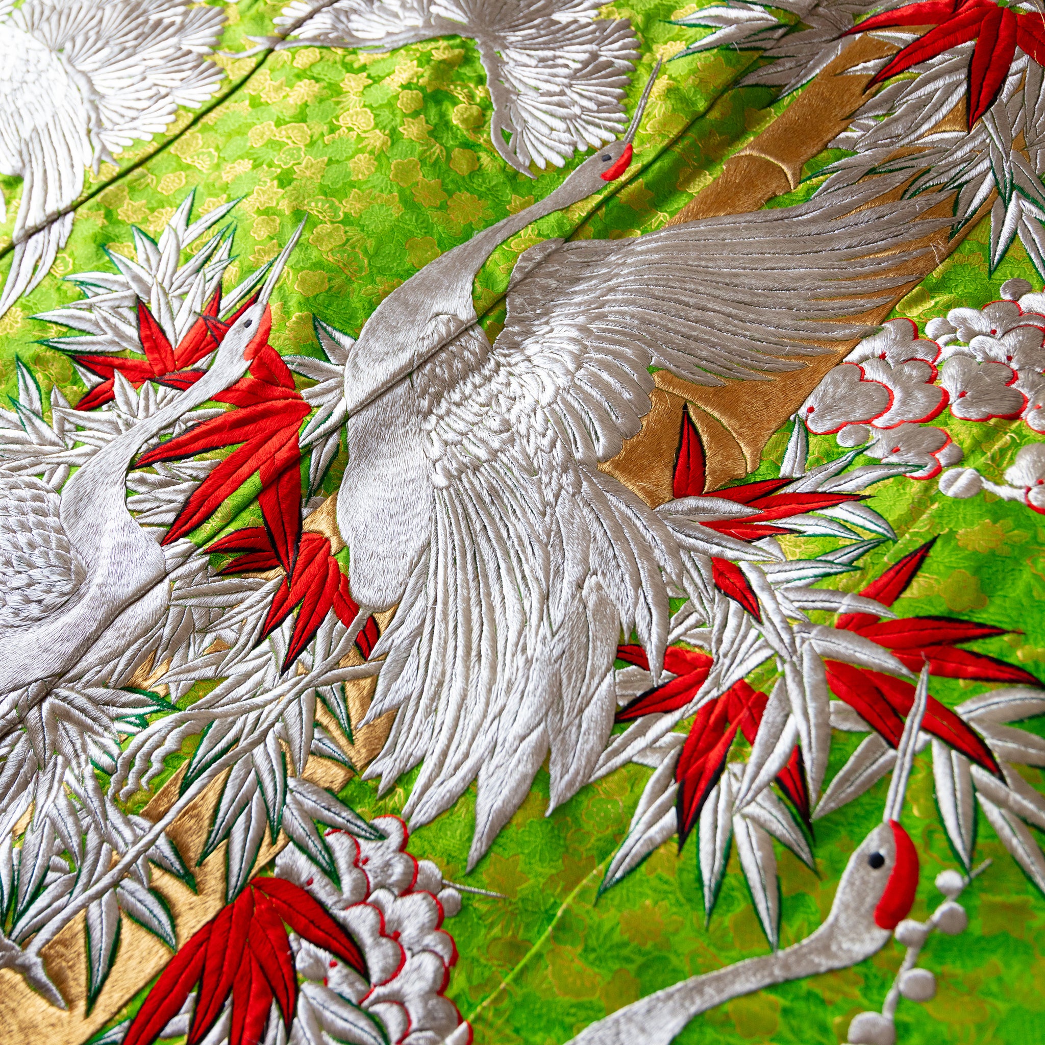 Close-up of the intricate silk embroidery detailing floral motifs along the kimono’s edge, highlighting craftsmanship and