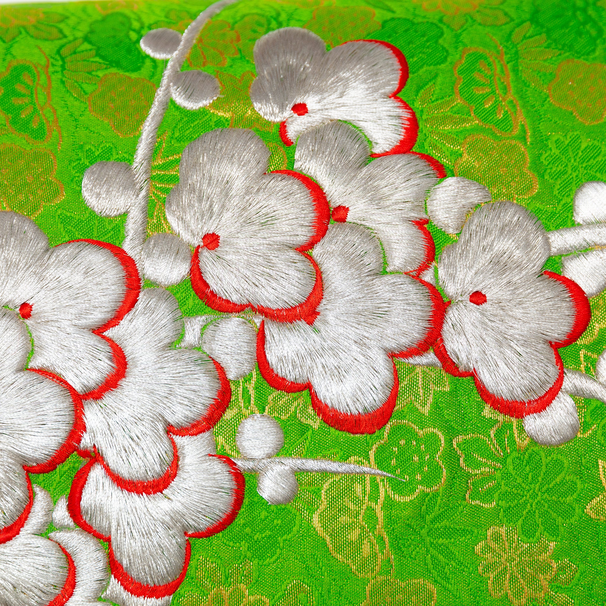 Close-up of silver blossom embroidered detail on the green silk kimono pillow fabric with snowdrift satin backing