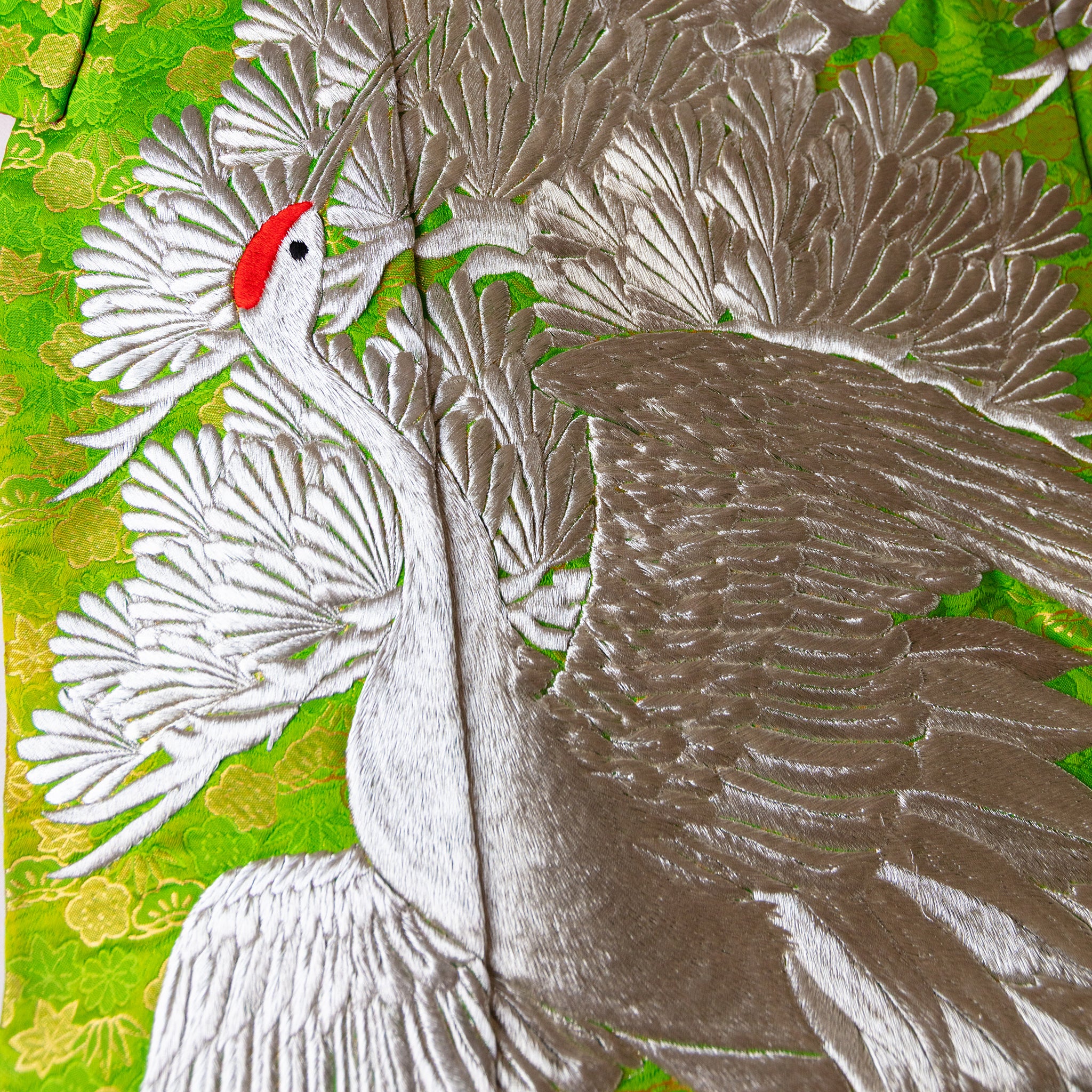 Close-up of the intricate silk weave and subtle floral embroidery on the vintage kimono blanket from a slightly angled