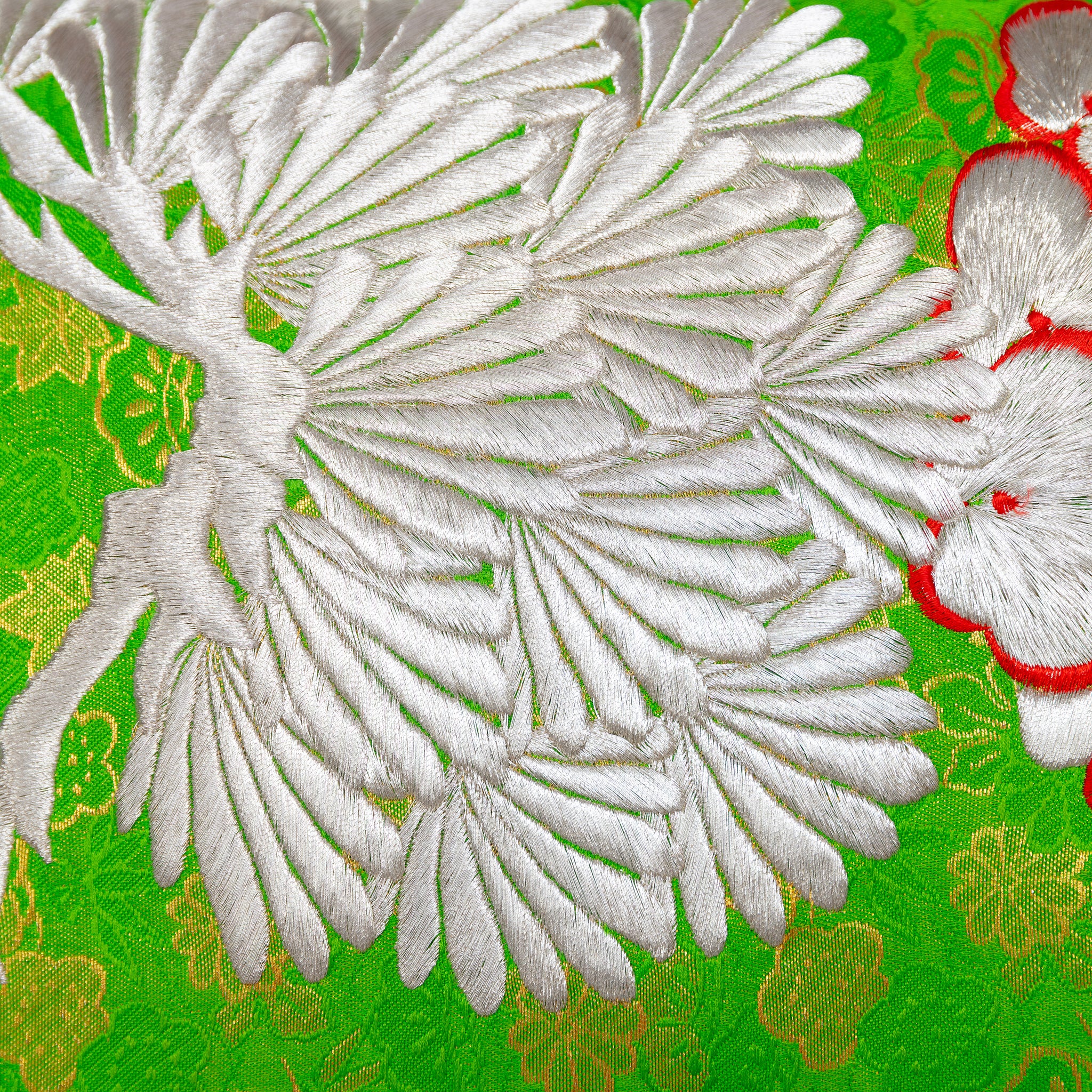 Close-up of the Green Silk Kimono Pillow's silver blossom embroidery and snowdrift satin back fabric detail from a diagonal