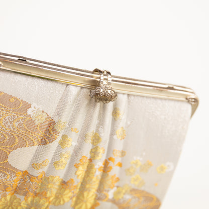 Clutch bag with gold floral pattern and fancy silver clasp and plain silver frame on a white background