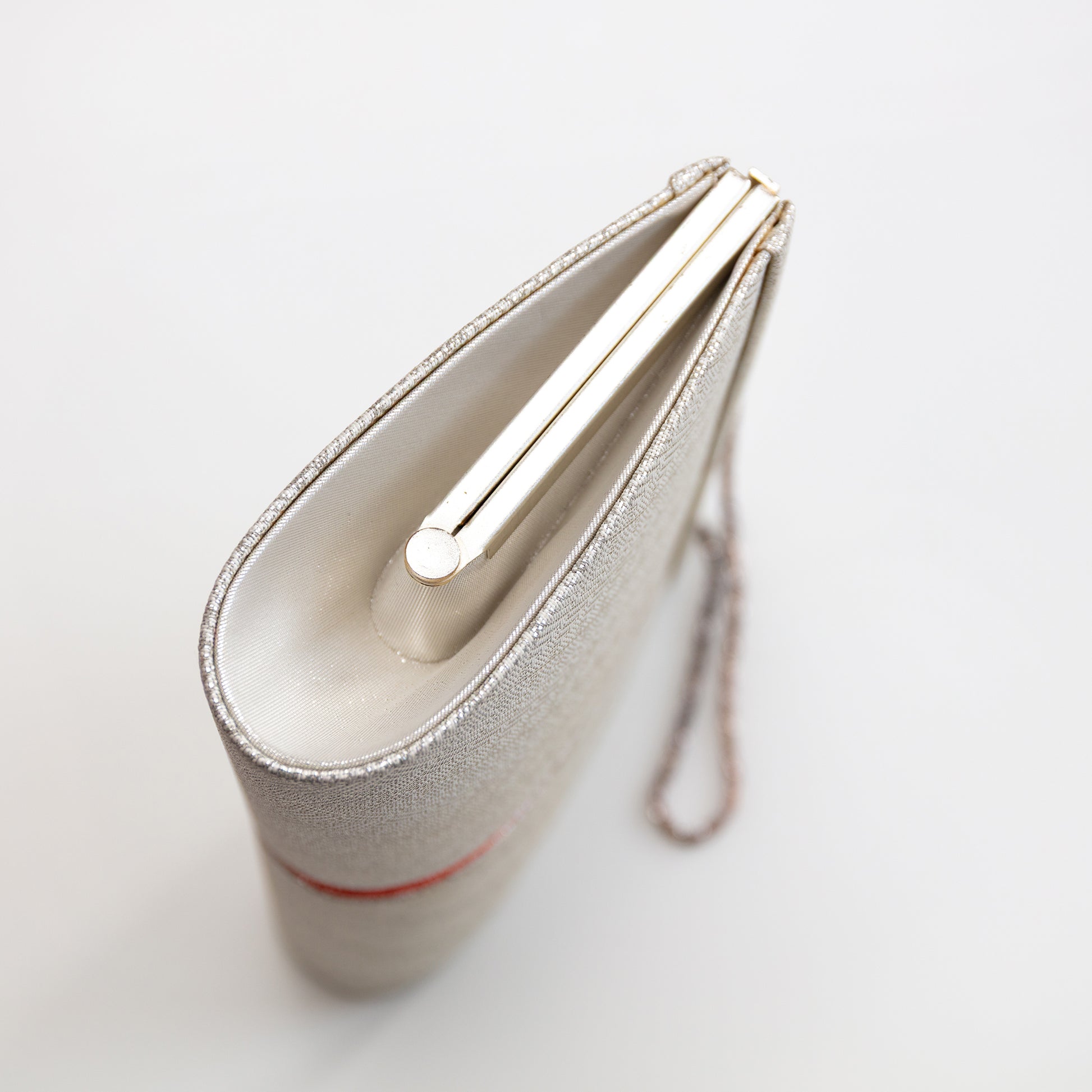 Side view of a silver clutch bag with a strap on a light gray background