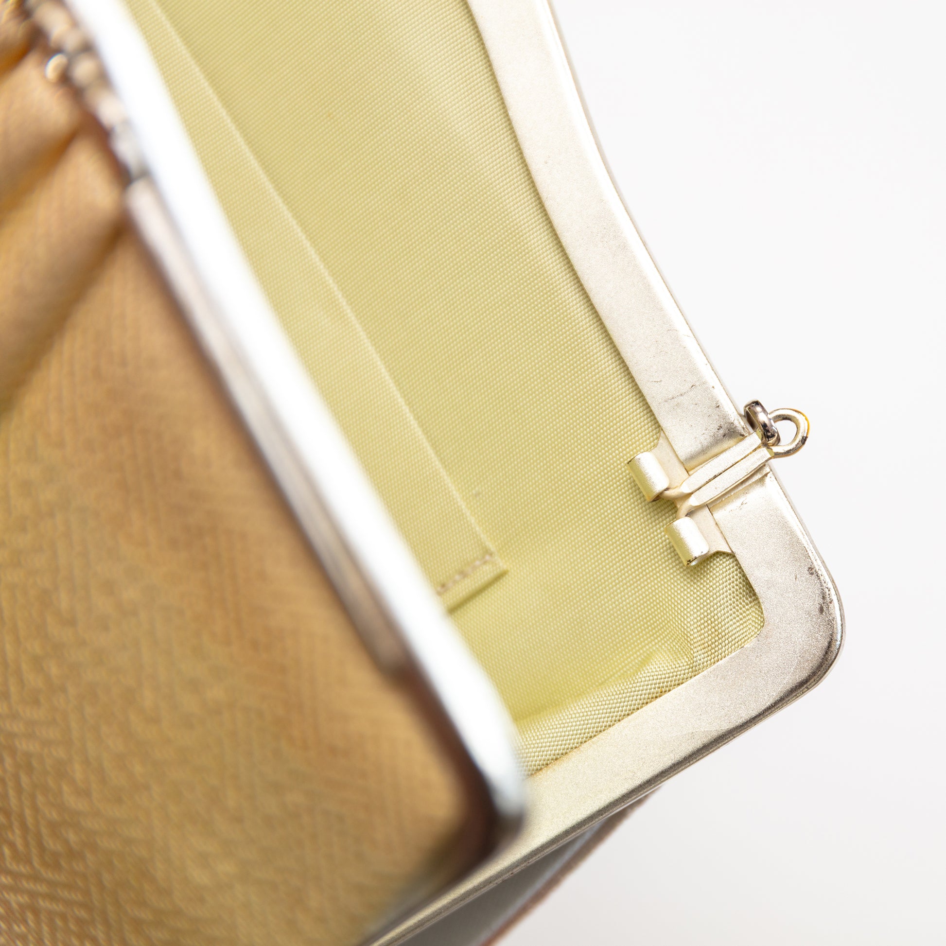 Close-up of a peach to cream silk 1950s clutch bag with a cream silk interior on a white background. The strap hinges tuck in or out.