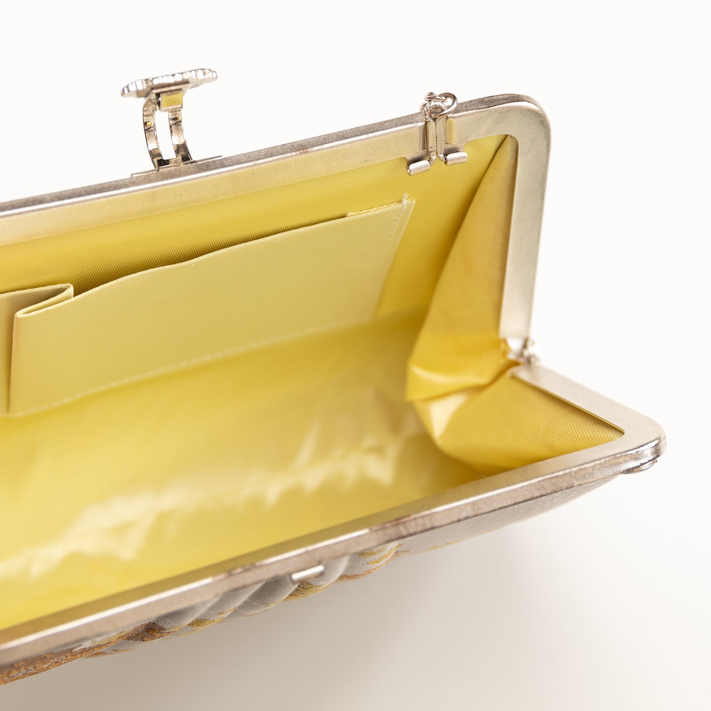 Silver ivory clutch bag with cream silk lining and a metallic frame on a white background