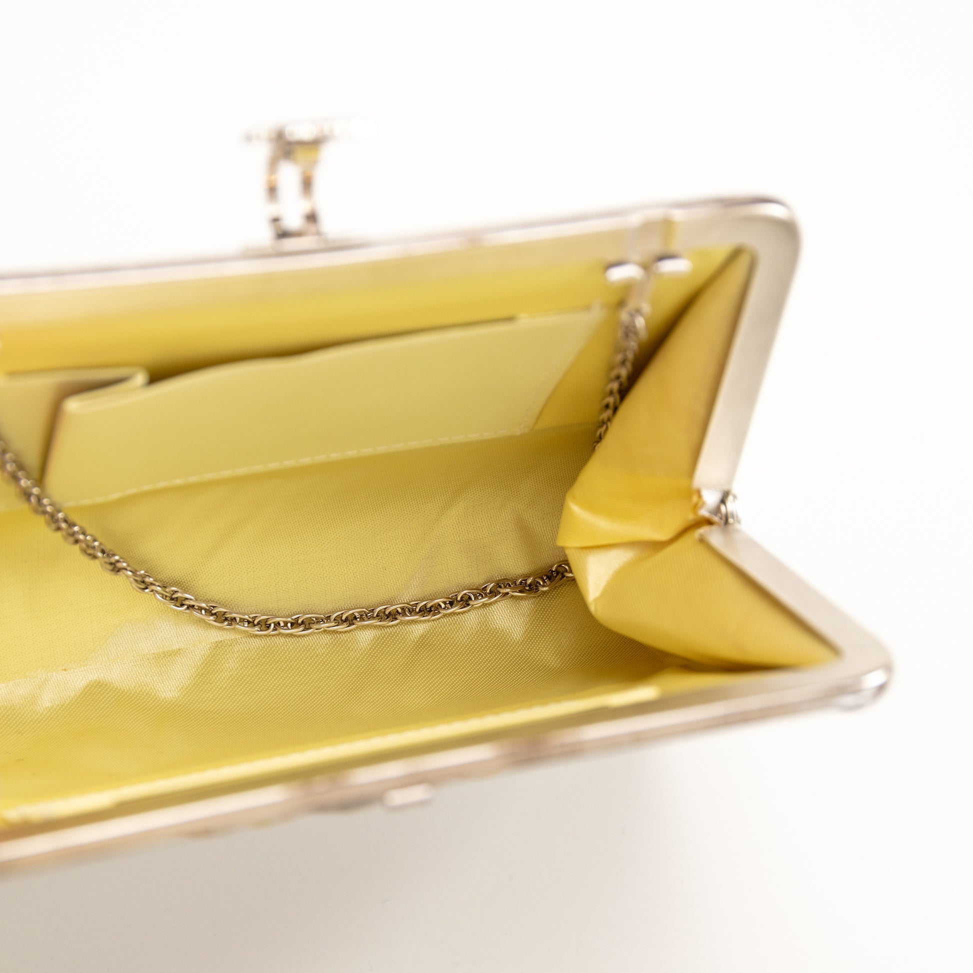 Vintage Japanese clutch bag with a cream silk lining and silver metal chain strap on a white background