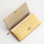 Close-up of gold metallic kimono floral embroidery on clutch’s front, showcasing intricate threadwork and textured fabric