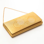 Close-up of the gold foldover clutch’s floral embroidery detail, highlighting intricate metallic threadwork and textured