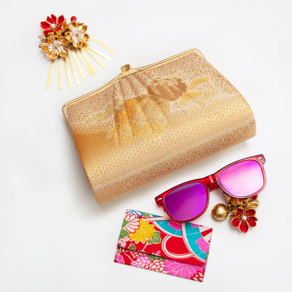 Gold clutch, sunglasses with pink lenses, floral cardholder, and decorative hairpin on a white background