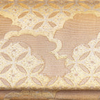 Close-up of the gold silk envelope clutch’s intricate shippo cloud embroidery and shimmering texture from a side angle